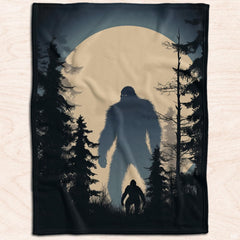 Dual Sasquatch moonlit throw blanket displayed on a bed.