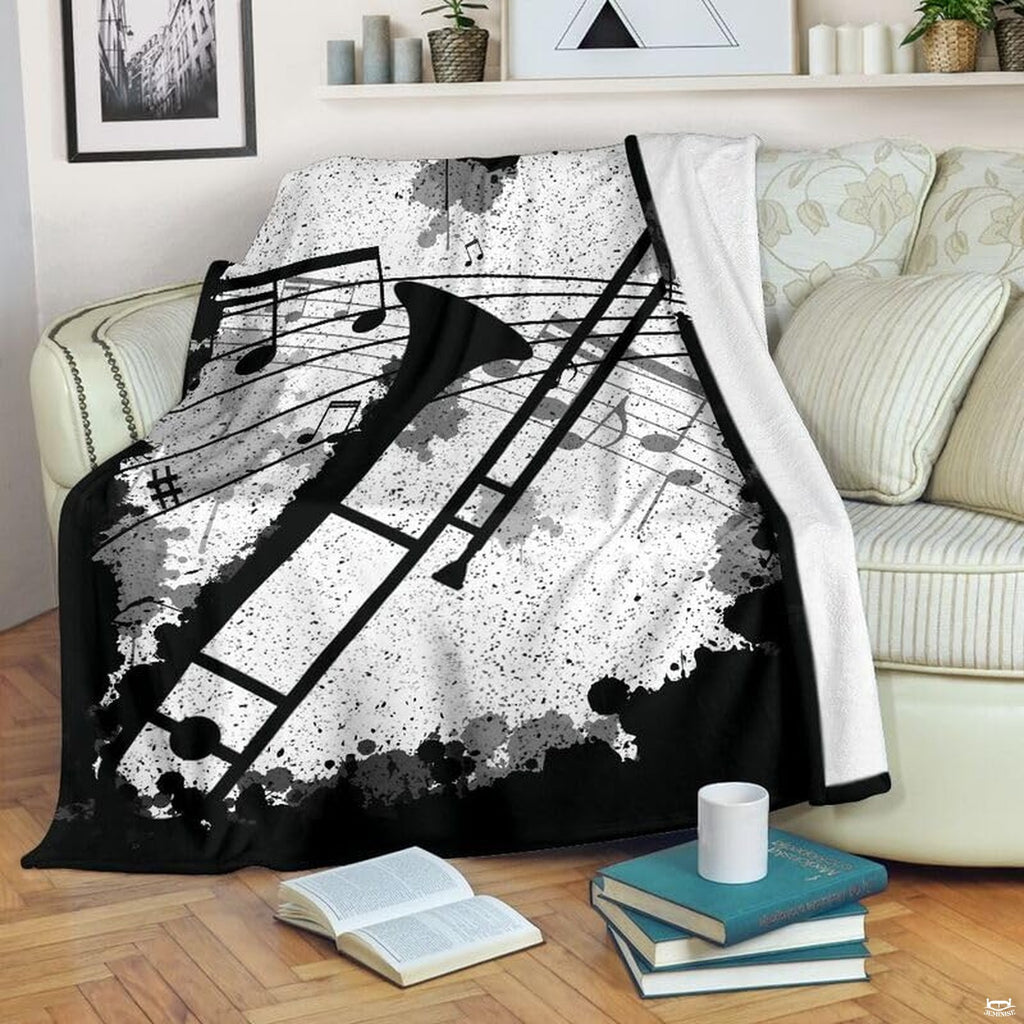 Trombone music blanket draped over an armchair beside a stack of books and a cup.