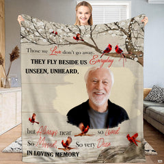 Woman holding up red cardinal memorial blanket displaying perched birds and remembrance quote