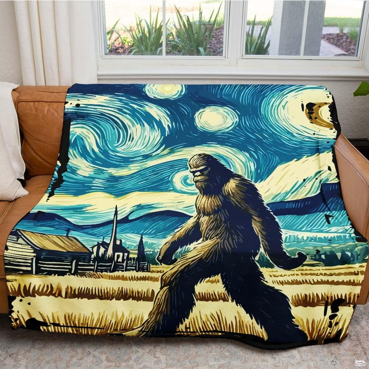 Starry night Sasquatch blanket draped neatly over a brown leather living room sofa