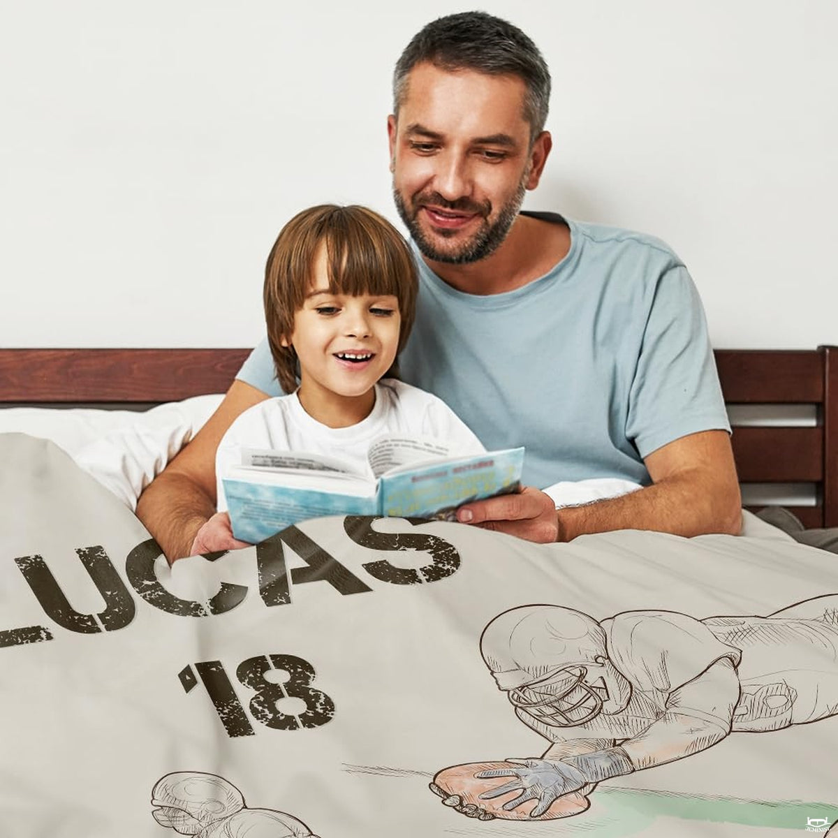 Father and child reading in bed covered by football player sports sketch throw blanket