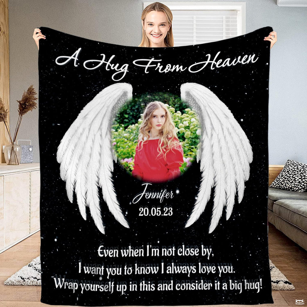 Woman holding up black angel wings memorial blanket displaying starry backdrop and white feathered wings