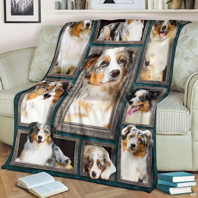 Australian Shepherd throw blanket styled across a living room sofa near stacked books and a cup.