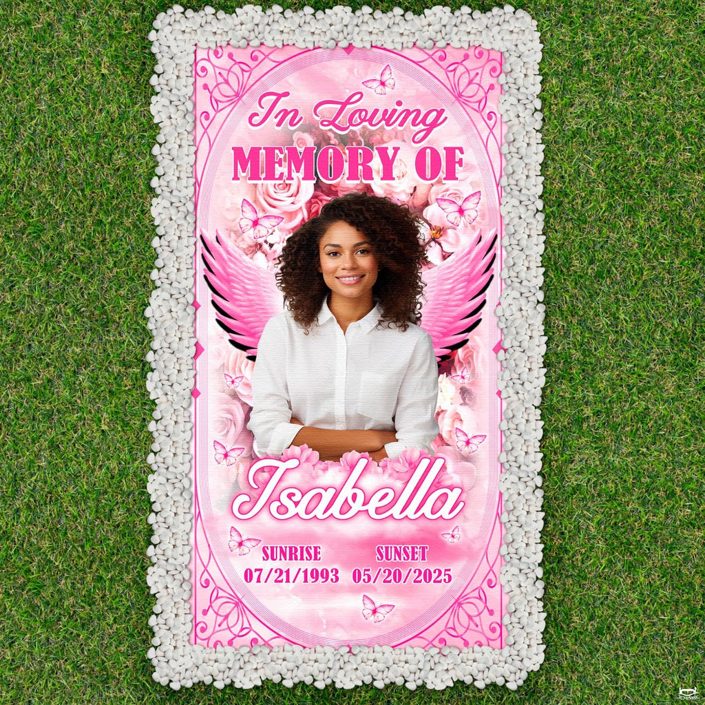 Aerial display of pink angel wings cemetery tribute bordered by white pebbles on green lawn.