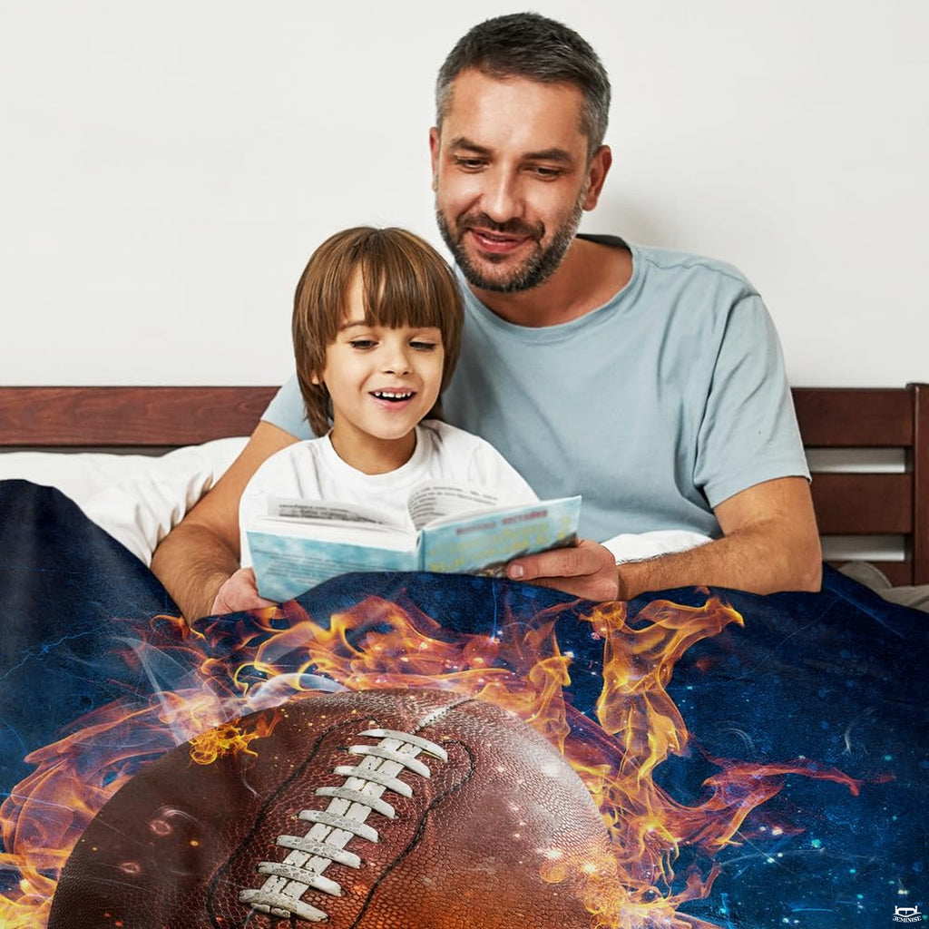 Adult and child reading in bed draped under fiery football graphic throw blanket