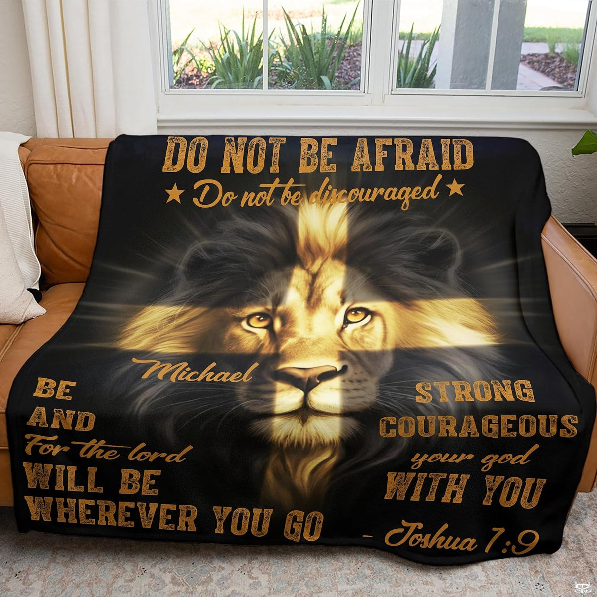 Throw blanket draped across living room seating near a window displaying lion and cross art.