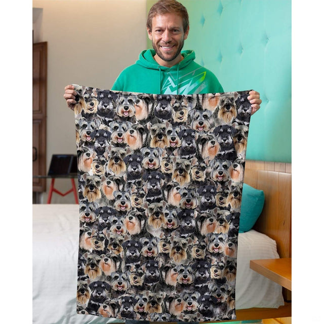 Person holding up a Schnauzer dog collage blanket in an indoor domestic room setting.
