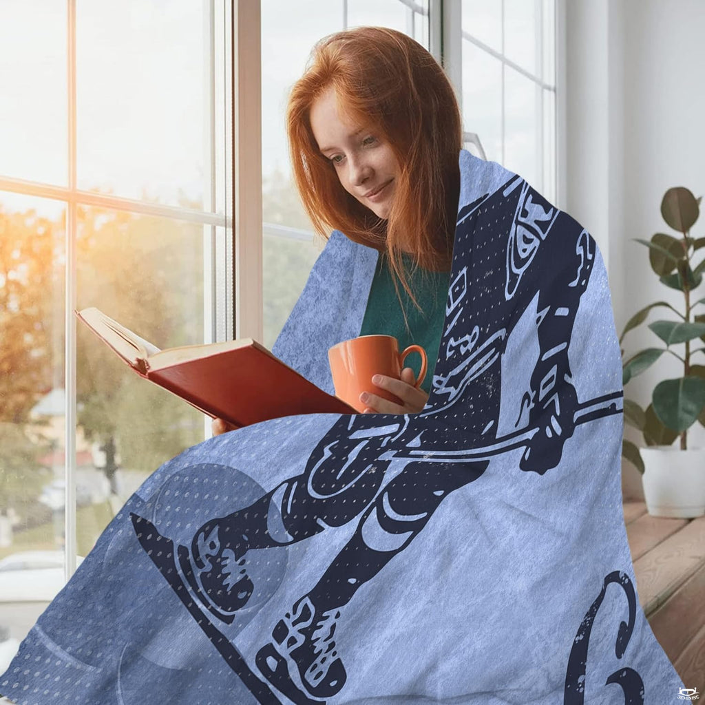 Ice hockey skater design blanket draped over a person reading by a sunny window.