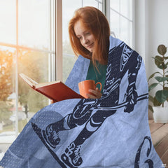 Ice hockey skater design blanket draped over a person reading by a sunny window.