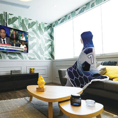 Lifestyle interior presentation showing soccer artwork draped on a sofa in a modern media room.