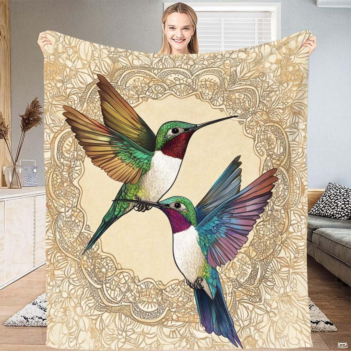Two jewel-toned hummingbirds framed by lace filigree medallion on ivory blanket.