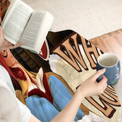 Angled perspective of reader girl throw blanket displaying rich book spine colors and draped folds.