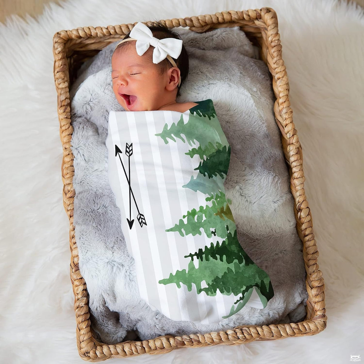 Nursery lifestyle view of an infant resting in a woven basket wrapped in the evergreen forest graphic.