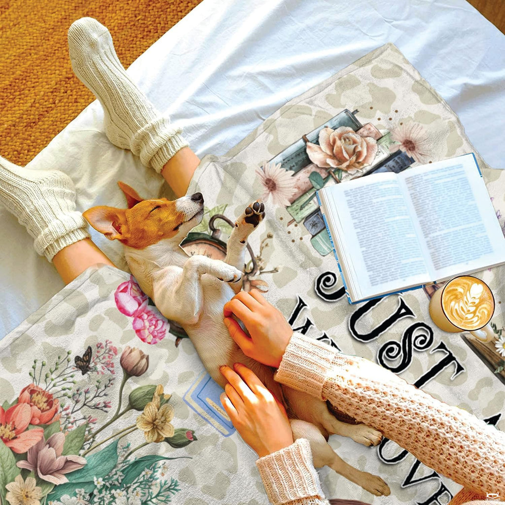 Overhead lifestyle showing folded novel enthusiast coverlet with sleeping puppy on white linens.