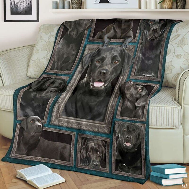 Black Labrador Retriever throw blanket styled across a living room sofa near stacked books and a cup.