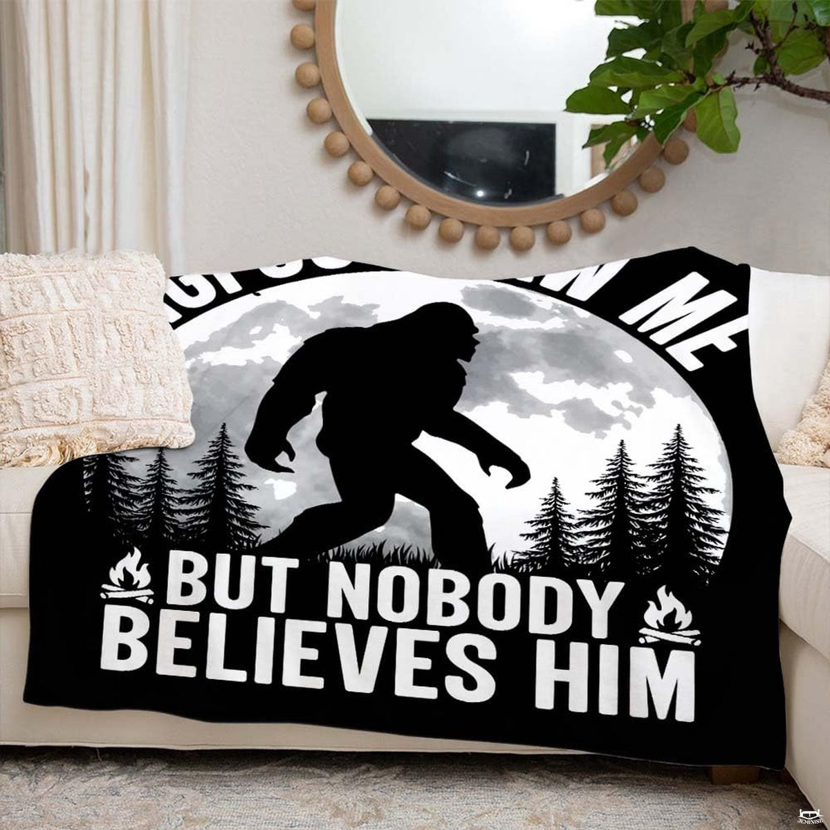 Folded nocturnal Bigfoot pine forest throw blanket resting on wooden table displaying full moon print
