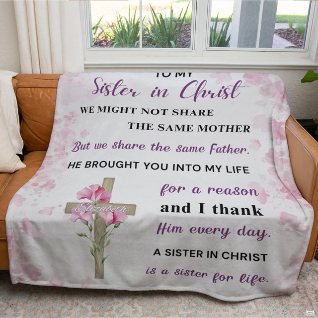 Floral cross watercolor blanket draped over couch in front of window.