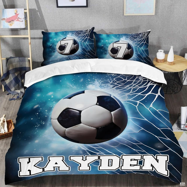 Close-up perspective of soccer bedding detailing cyan wave ripples, ball pentagons, and collegiate typography