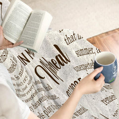 Close view of individual holding mug with memorial blanket draped over knees.