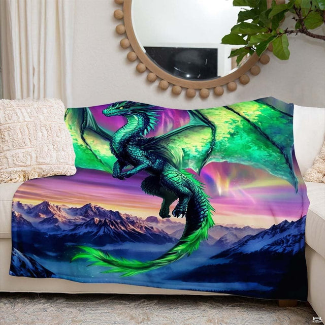 Close-up view of aurora dragon throw blanket highlighting radiant green wings and scenic alpine details.