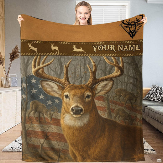 Model holding up an outdoor blanket displaying a whitetail buck before an American flag and woodland trees.