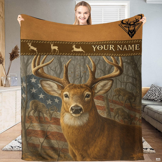 Model holding up an outdoor blanket displaying a whitetail buck before an American flag and woodland trees.