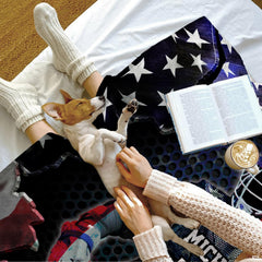 Overhead lifestyle view of lacrosse sports throw blanket draped on bed beside reading book and dog.