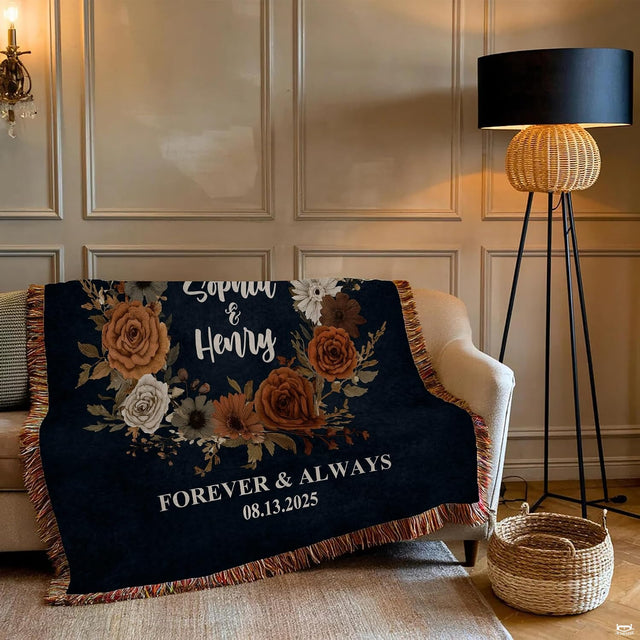 Close-up of terracotta roses, cream daisies, and dried botanical foliage on a dark navy blanket