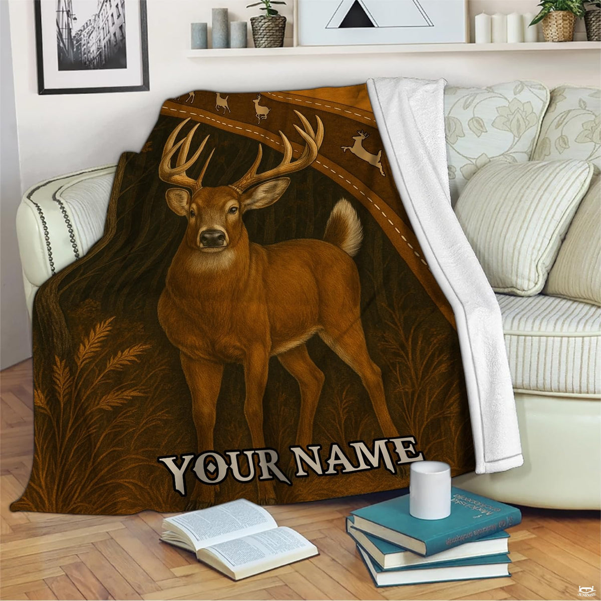 Woodland whitetail buck blanket draped across an indoor living room couch next to stacked books.