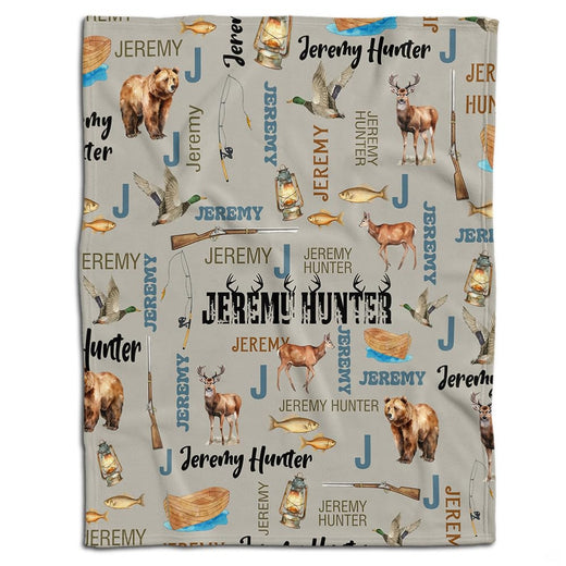 Rustic throw blanket with illustrated bears, deer, mallards, and outdoor gear pattern on beige