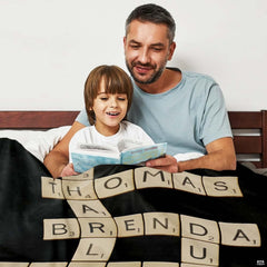 Close-up detail of cream wooden letter tiles with point scores against solid black background.