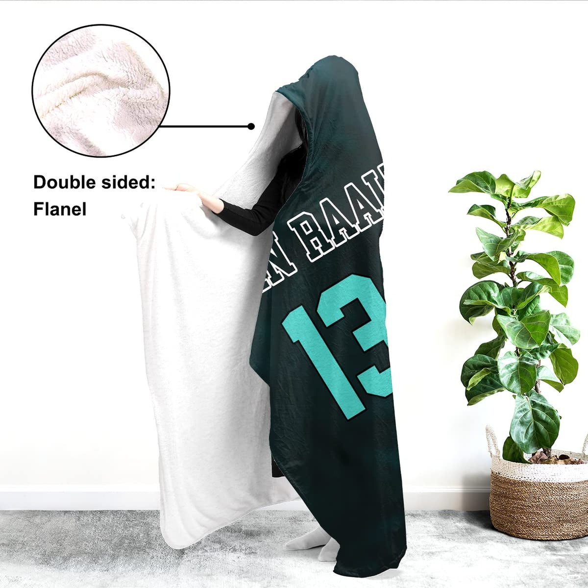 Person modeling the sports graphic textile indoors beside a large potted green fiddle leaf fig plant.
