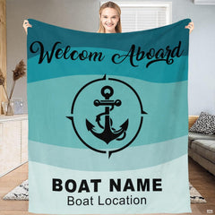 Woman holding up nautical anchor blanket displaying teal wave stripes and compass emblem