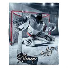 Hockey goalie in thematic accent defensive stance blocking the goal on an arena ice rink with crisp reflections.