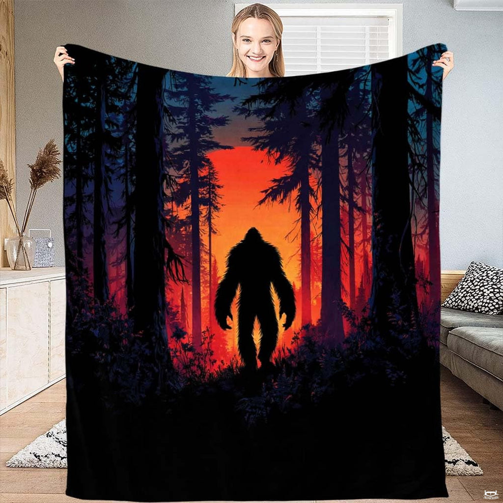 Sunset Bigfoot silhouette throw blanket showing Sasquatch among pine trees backlit by glowing red sunset