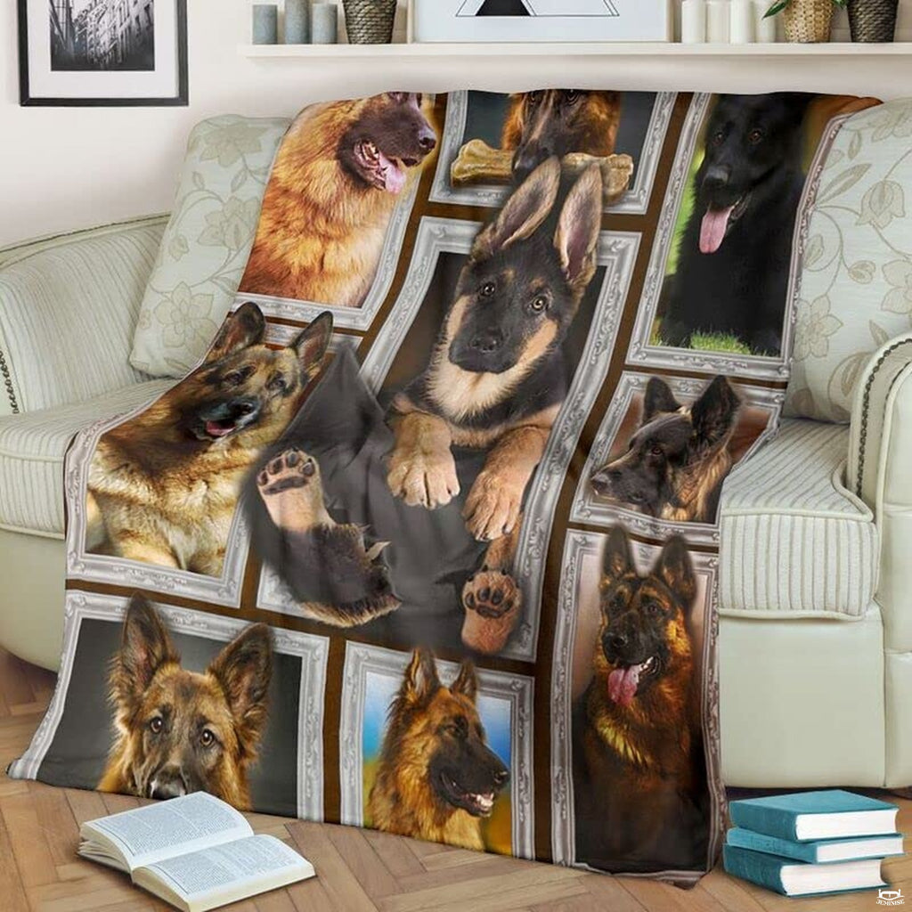 German Shepherd throw blanket styled across a living room sofa near stacked books and a cup.