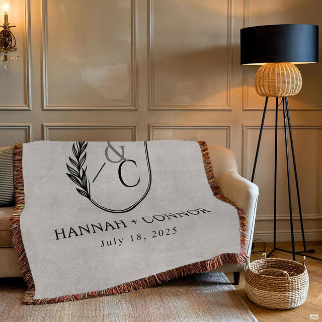 Close-up of double-oval botanical crest with olive leaves and refined serif lettering on a blanket
