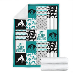 Folded blanket showing teal athletic patchwork panels and wrestler silhouette artwork.