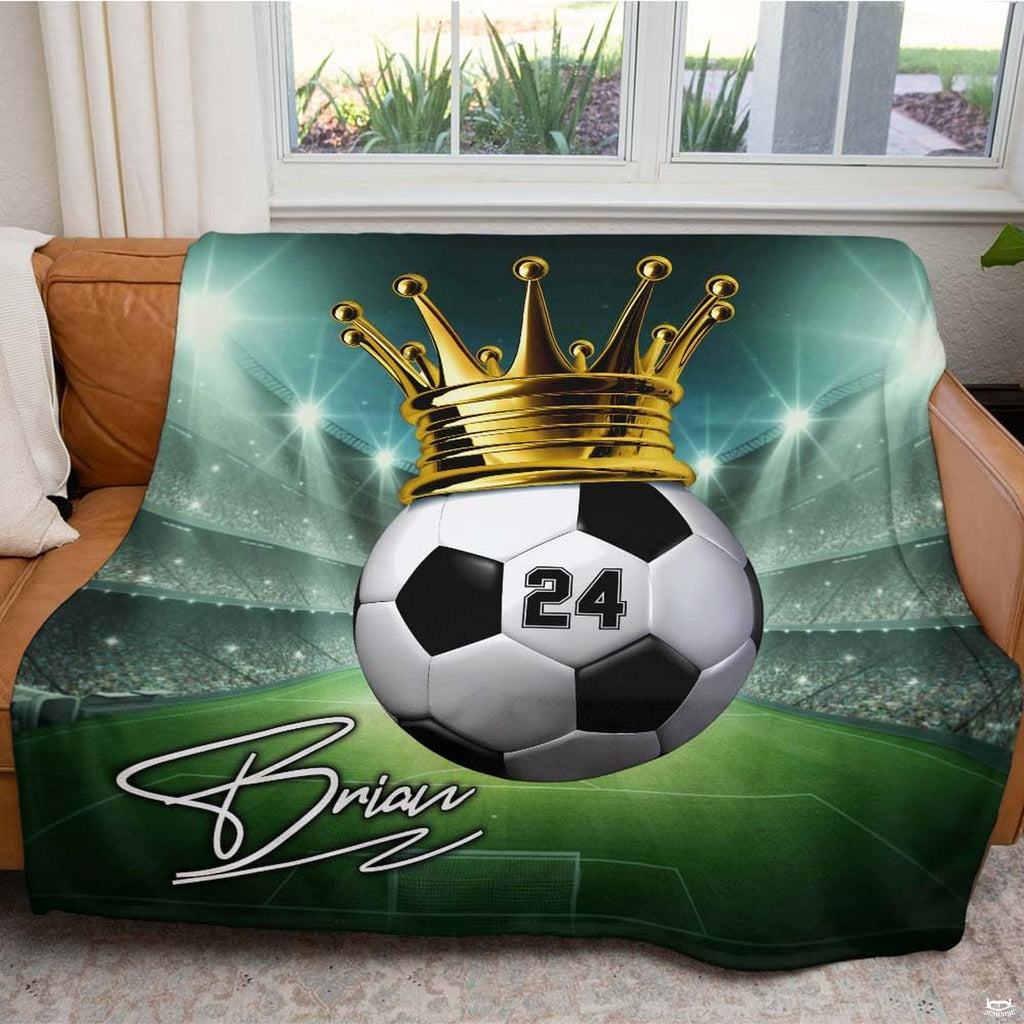 Full display of crowned soccer ball athletic graphic blanket arranged across a living room sofa.