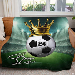 Full display of crowned soccer ball athletic graphic blanket arranged across a living room sofa.