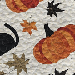 Close view of illustrated seated black cats and amber maple leaves on autumn bedding decor.