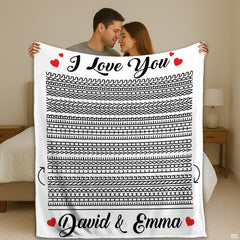 Couple holding up optical illusion throw blanket featuring hidden line art and red hearts in bedroom