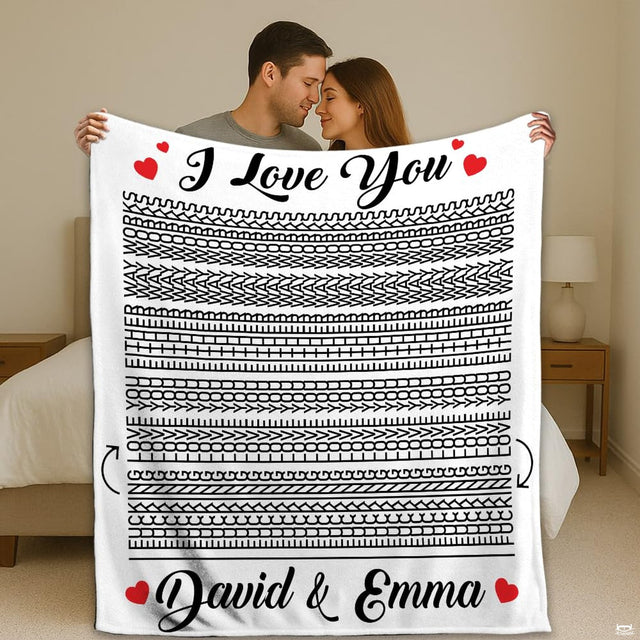 Couple holding up optical illusion throw blanket featuring hidden line art and red hearts in bedroom