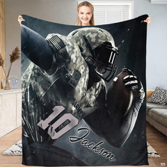 Woman holding up camo football throw blanket displaying military patterned uniform and helmet visor