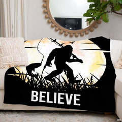 Folded fishing Bigfoot moon silhouette throw blanket resting on wooden table displaying harvest moon
