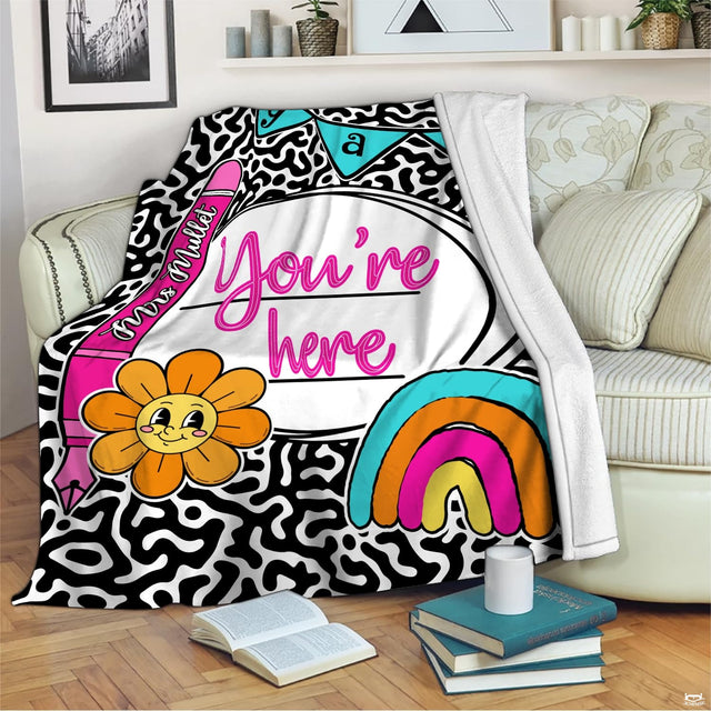 Retro cartoon flower graphic in bright yellow and orange centered on black and white cow print bedding.