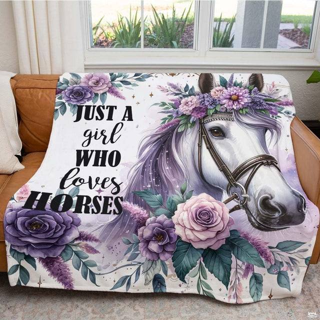 Woman holding open purple floral white horse portrait throw blanket in bright room