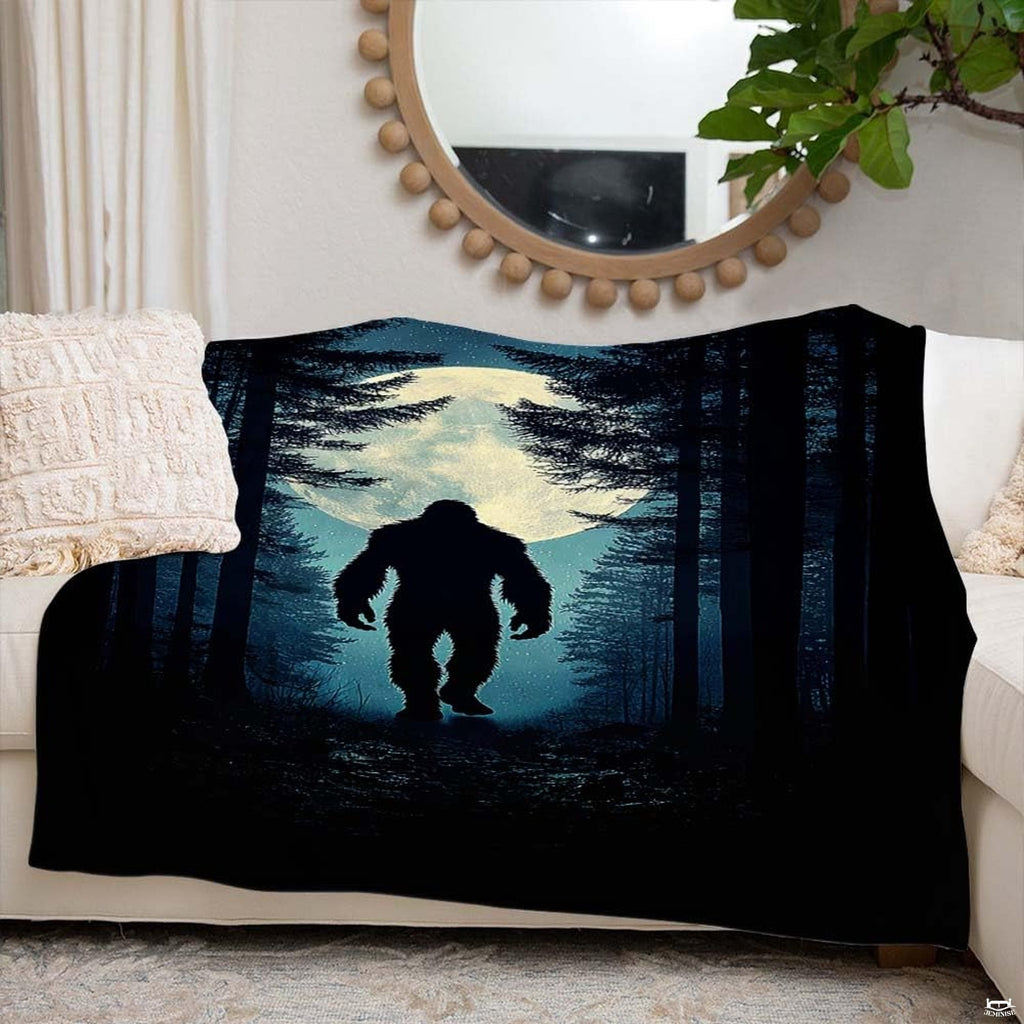 Glowing moon Bigfoot blanket styled across an indoor couch beneath a round decorative mirror.