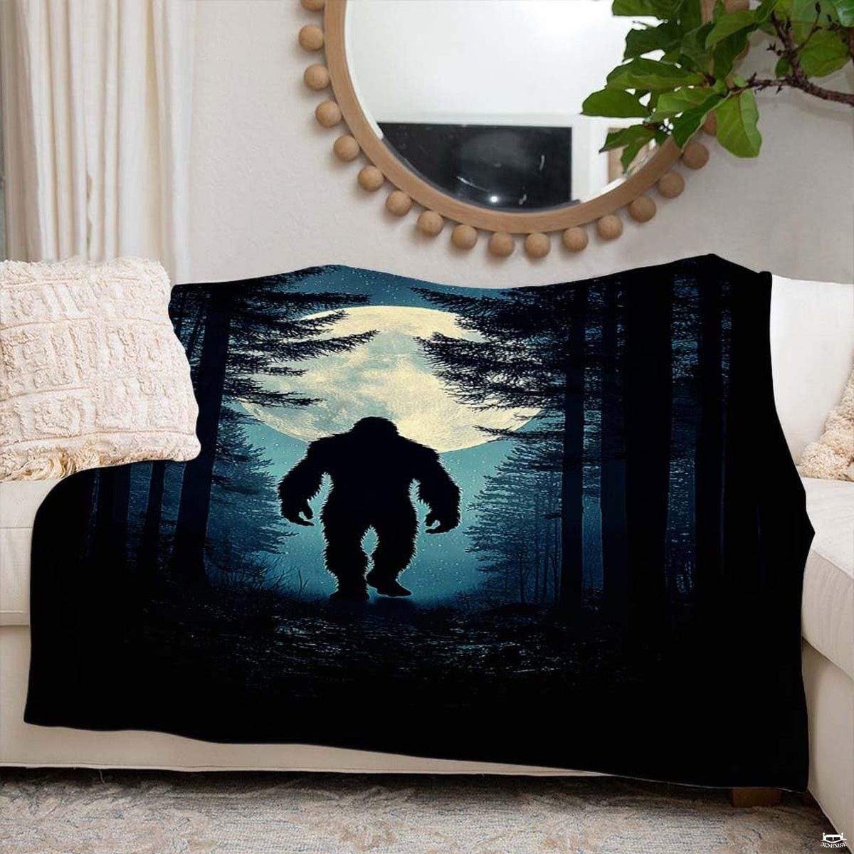 Glowing moon Bigfoot blanket styled across an indoor couch beneath a round decorative mirror.