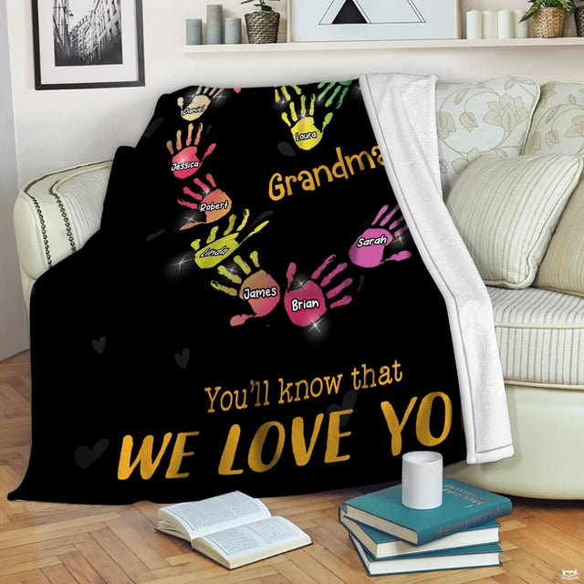 Close-up of vibrant pink, cyan, and yellow handprint art with glowing sparkles on black bedding.